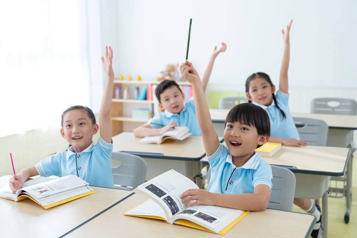 Children in class with their hands raised