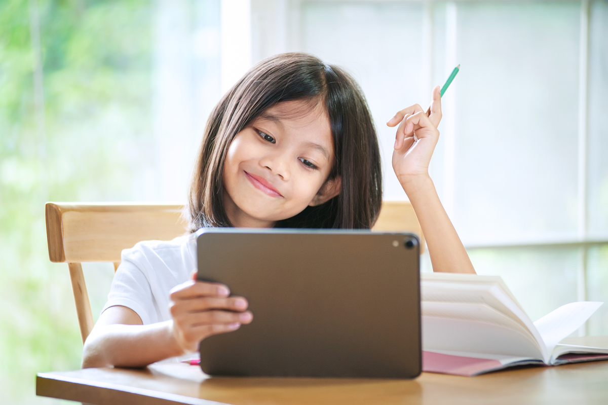 girl smiling and doing homework on her ipad