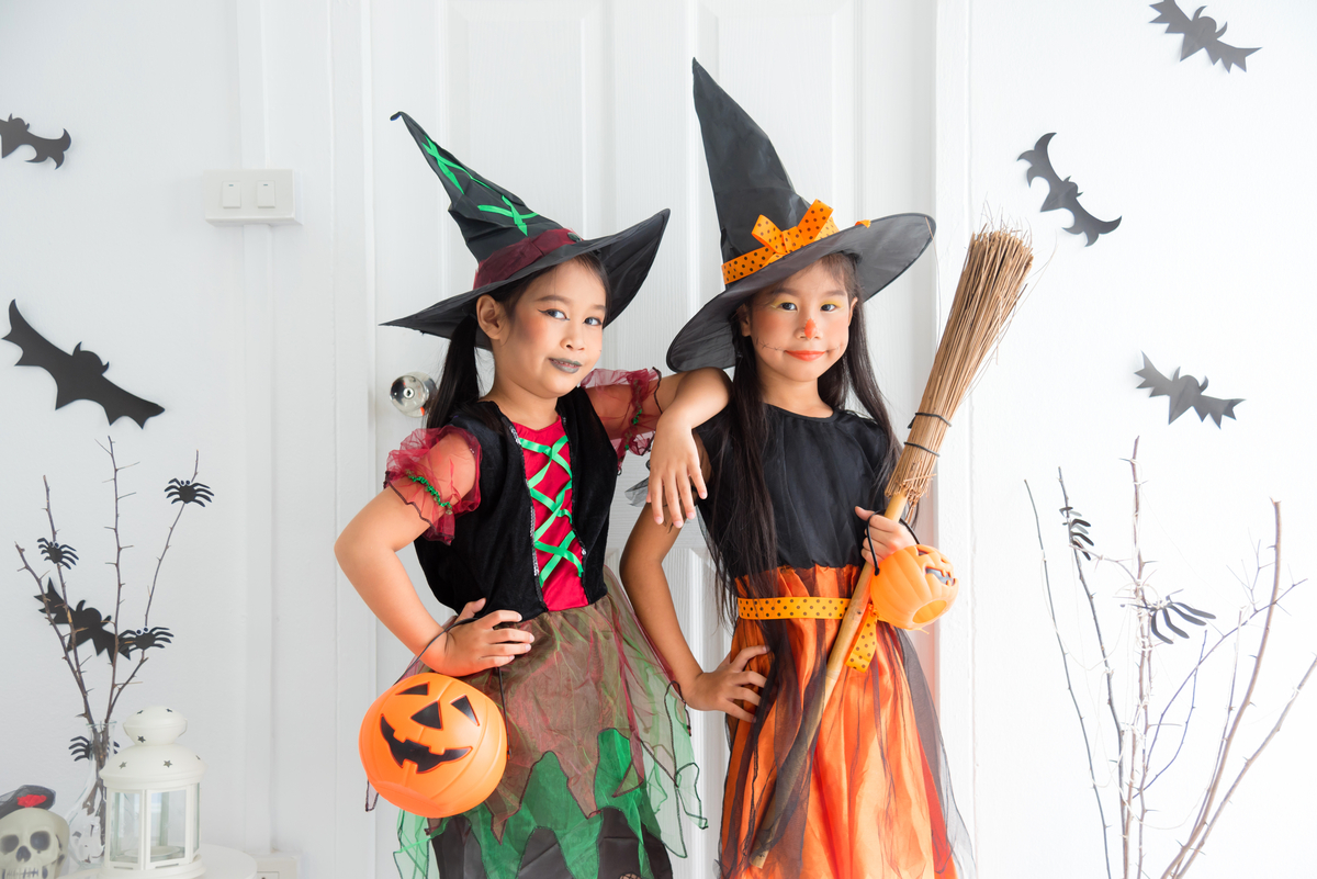 Free Halloween Math Worksheets for K2 to P5 students girls dressed up wear witch hat and holding broomsticks