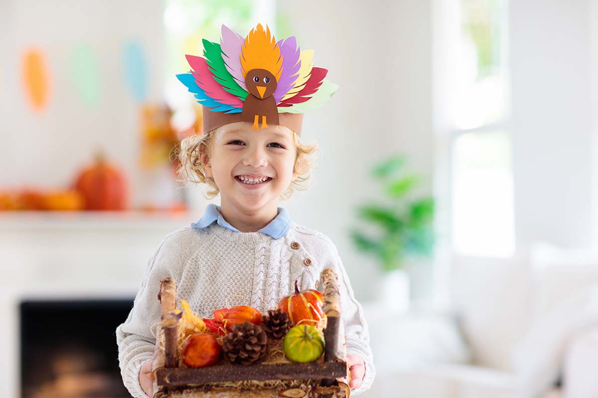 Free Thanksgiving 1st Grade Math Worksheets Kid with paper turkey hat holding fruit