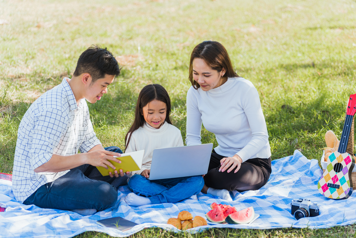 Math and outdoor learning family sitting outdoors with a laptop for enrichment