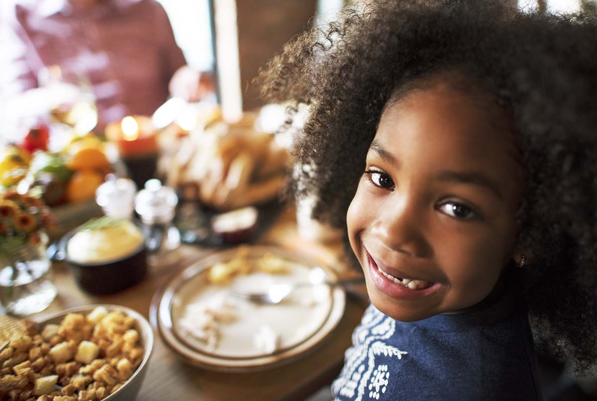 Girl Smiling at camera in front of thanksgiving dinner Free thanksgiving kindergarten worksheets
